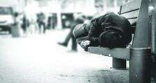 homeless man sleeping on the wooden bench