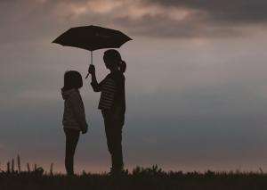 Child being sheltered under an umbrella - image Unsplash